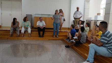 Doze pessoas. Crianças, jovens e sete adultos com um adulto a discursar numa sala do Centro Cultural Casapiano.