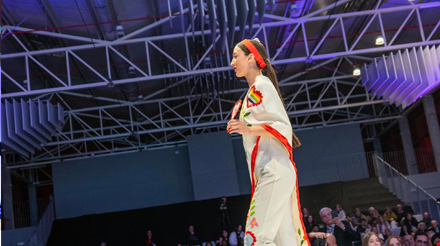 Jovem de vestido branco com a estrutura do edifício ao fundo