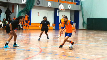 quatro jovens a jogar futsal perto de uma baliza num campo w