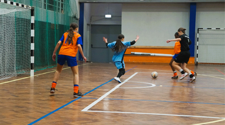 quatro jovens a jogar futsal perto de uma baliza num campo w